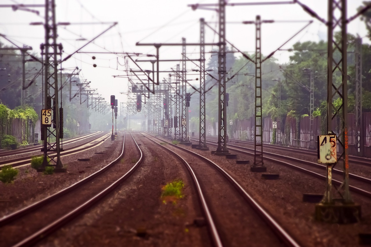 Eisenbahngleise, umgeben von Strommasten, verschwinden im Nebel